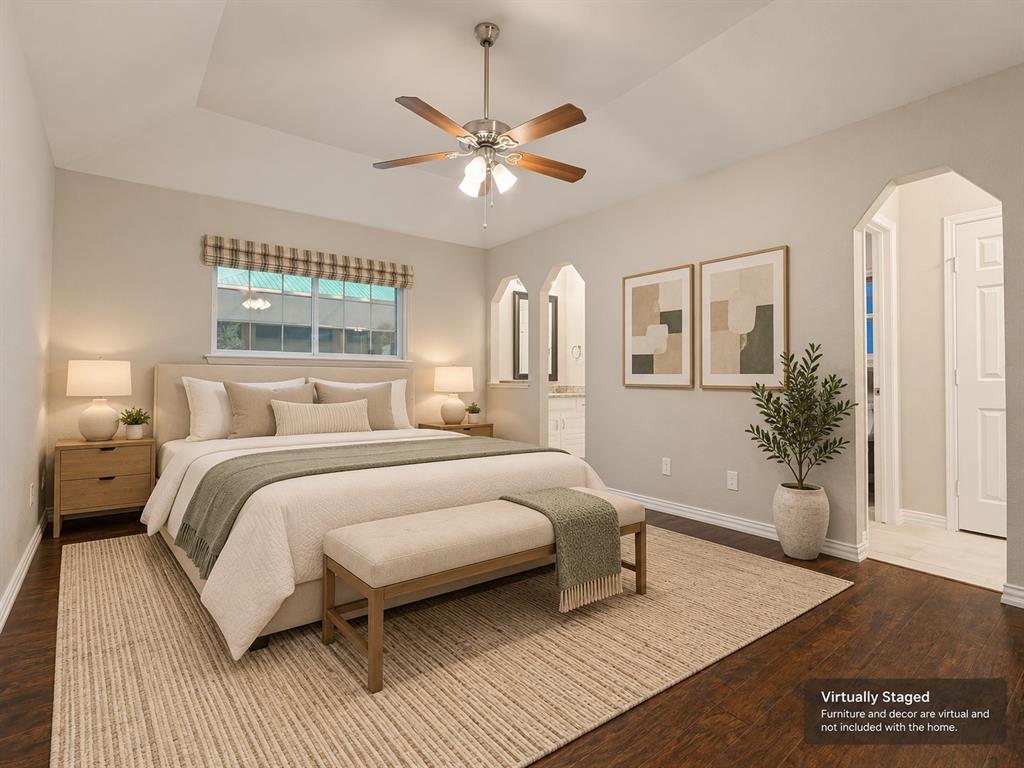 Tray ceiling featuring a central brushed-nickel ceiling fan with integrated lighting, wood-finish flooring, and arched architectural wall cutouts
