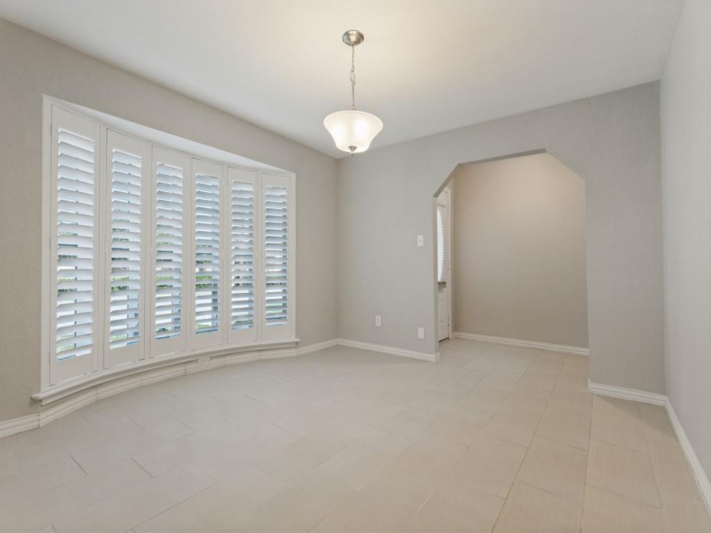 Bay window featuring white plantation shutters, neutral tile flooring, and a pendant light fixture with a bell-shaped glass shade