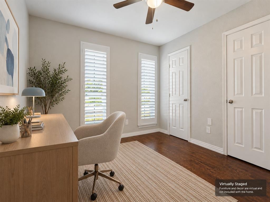 Room featuring wood-finish flooring, two windows with plantation shutters, a six-panel door, and a ceiling fan with integrated lighting