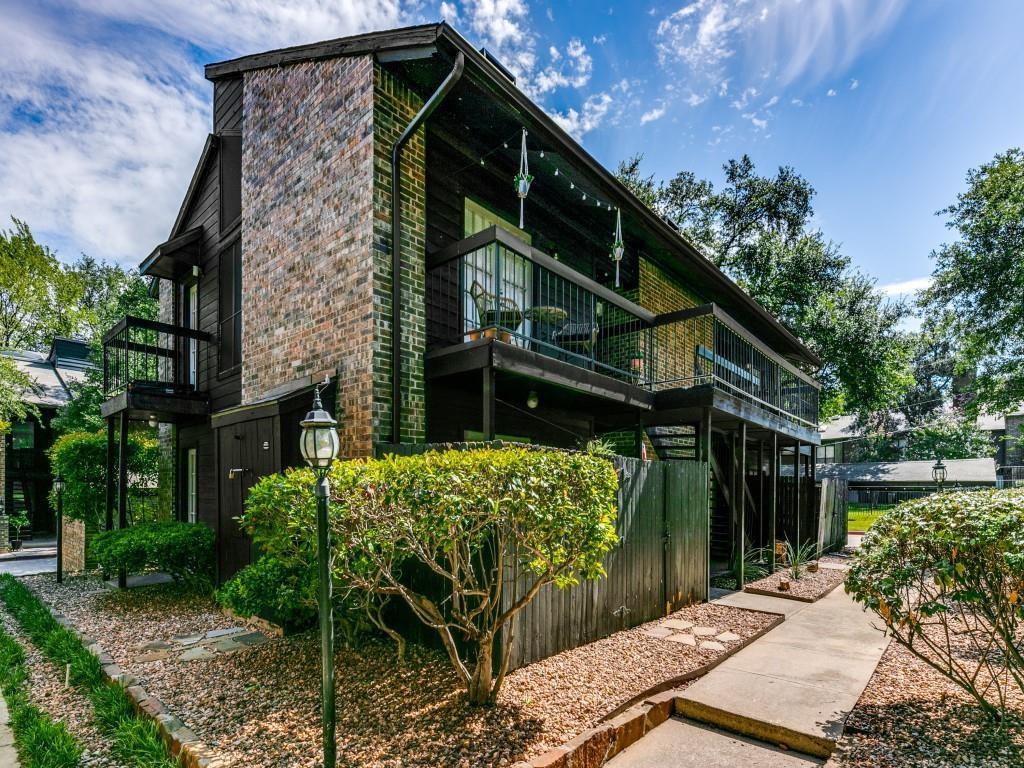 Multi-story exterior featuring multi-toned brick masonry, horizontal wood siding, second-level balcony, and concrete walkway