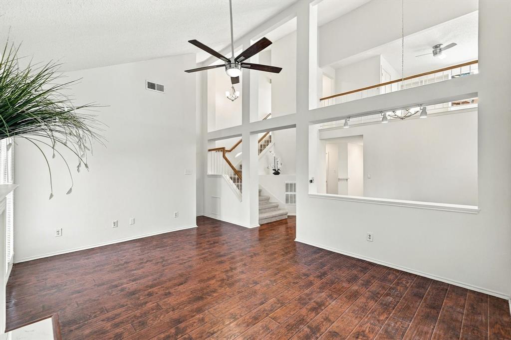 Vaulted ceilings, wood-finish flooring, recessed architectural cutouts, multi-level design, and central ceiling fan