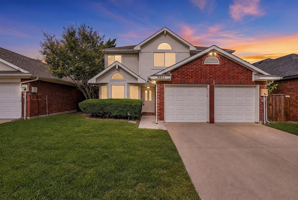 Two-story residence featuring a brick and siding facade, a double-car garage, a bay window, and arched architectural detailing Two-story residence featuring a brick and siding facade, a double-car garage, a bay window, and arched architectural detailing