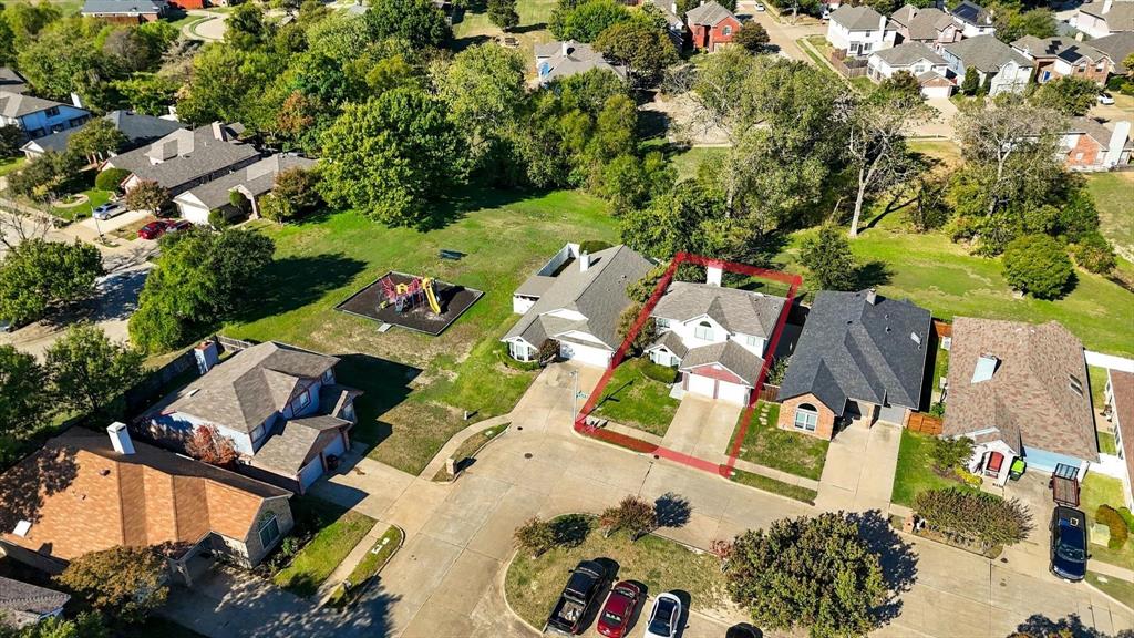 Aerial view of a residential property featuring a pitched shingle roof, integrated two-car garage, concrete driveway, and a fenced backyard
