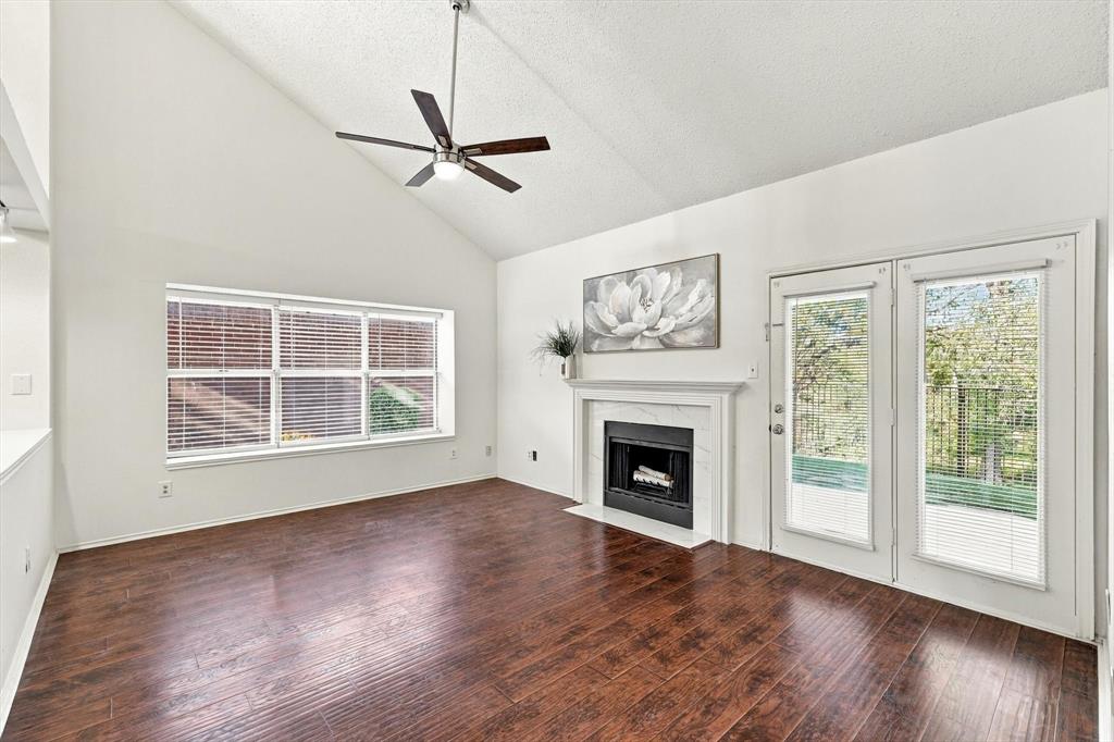 Vaulted ceilings, wood-finish flooring, fireplace with a decorative surround, ceiling fan, and dual-pane glass doors