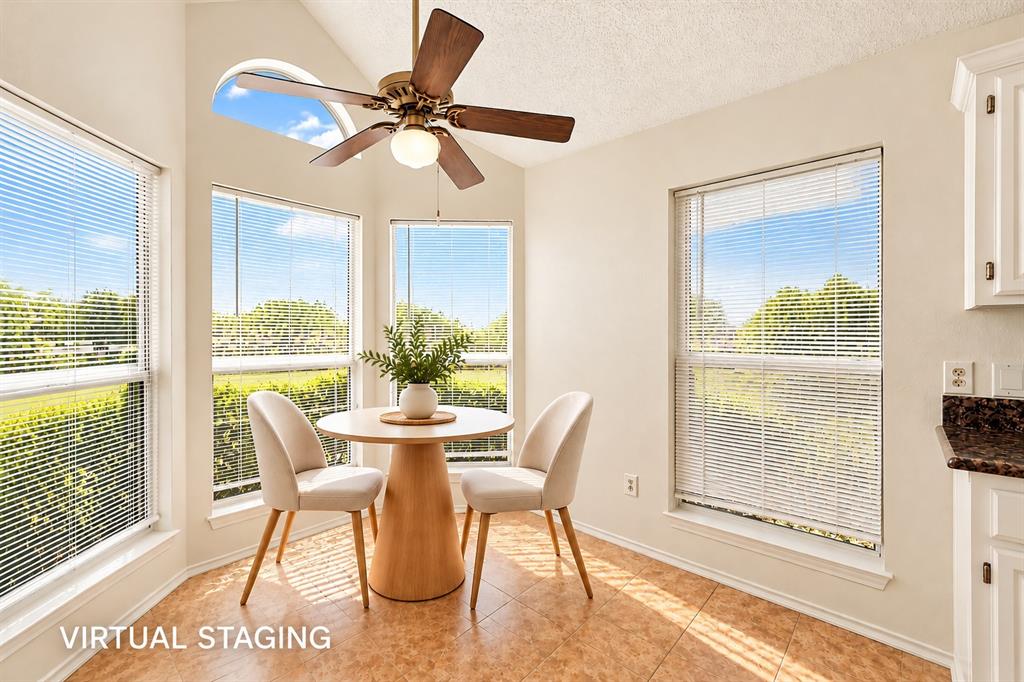 Vaulted ceiling with a centrally mounted ceiling fan, multiple large windows, arched transom window, and tile flooring