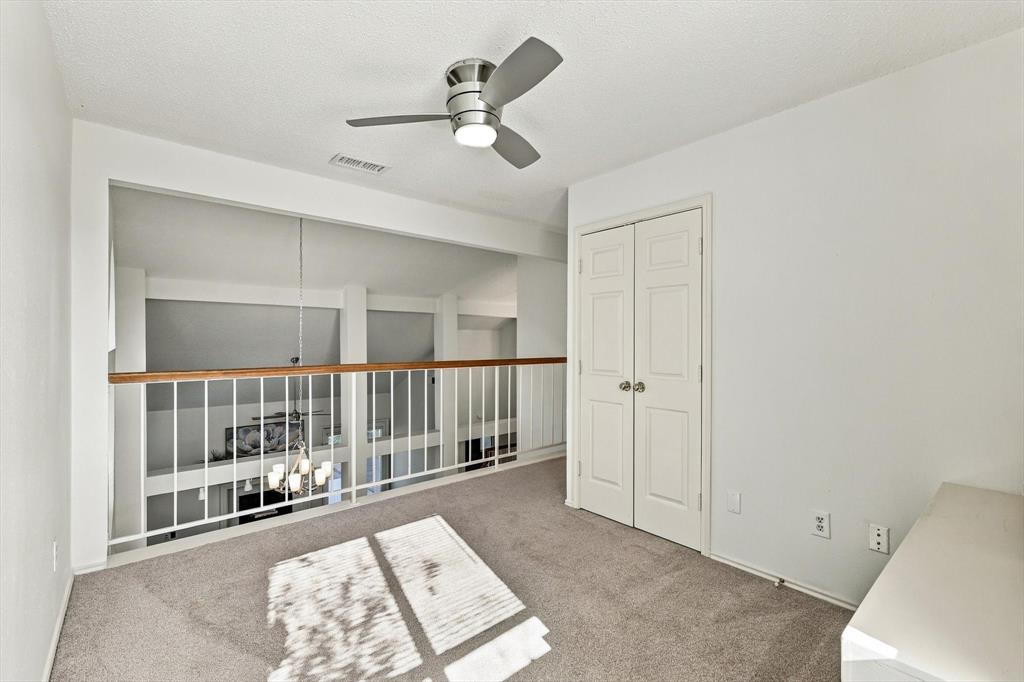 Neutral-toned carpet, metallic ceiling fan with integrated lighting, and white bi-fold closet doors, featuring a white metal railing with a wood-finish cap