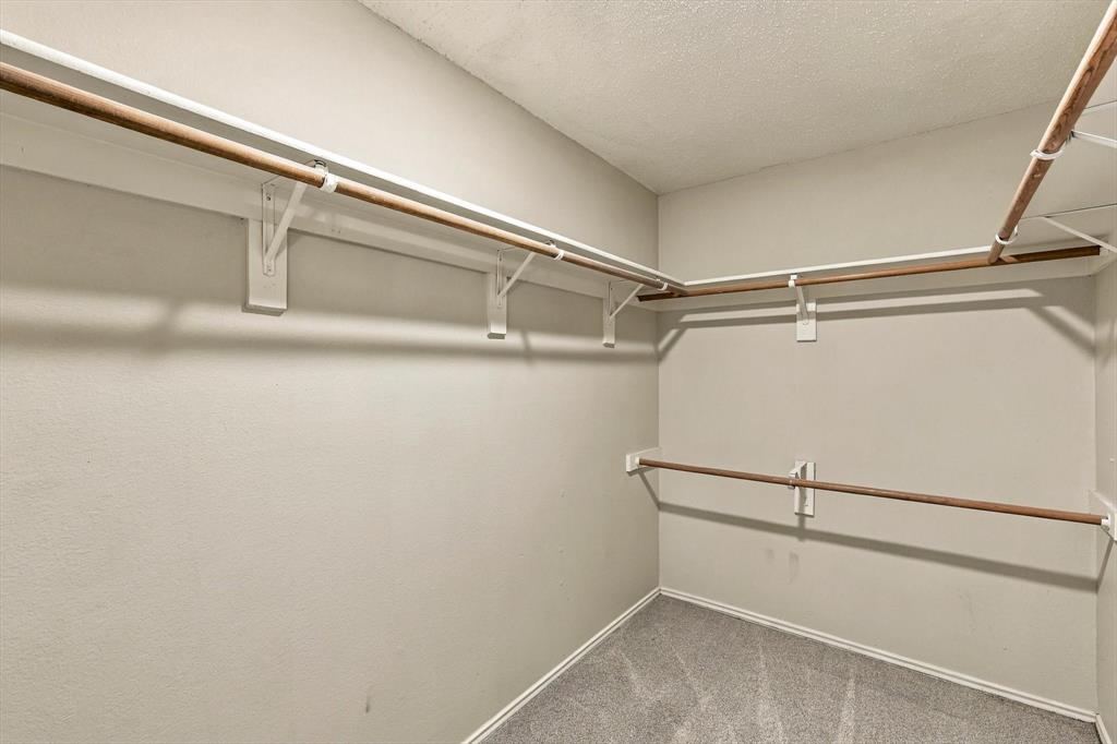 Walk-in storage space featuring multi-level hanging rods and integrated upper shelving