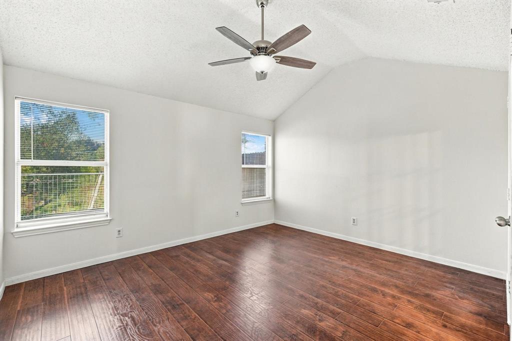Vaulted ceilings, wood-finish flooring, two dual-pane windows, and a ceiling fan with integrated lighting