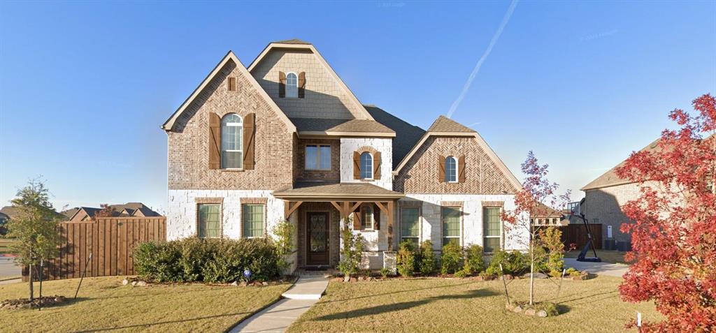 Two-story residence featuring a multi-gabled roofline, mixed brick and stone facade, decorative wood shutters, and a covered front porch with timber-frame accents