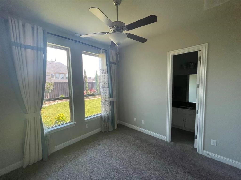 Neutral-toned interior featuring dual windows, carpeted flooring, and a ceiling fan with integrated lighting