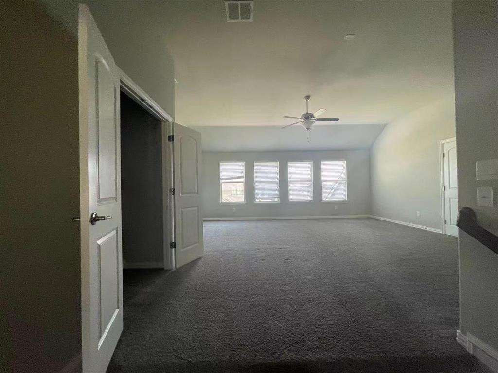 Open-concept area featuring a vaulted ceiling, neutral carpeting, four large windows, and a ceiling fan