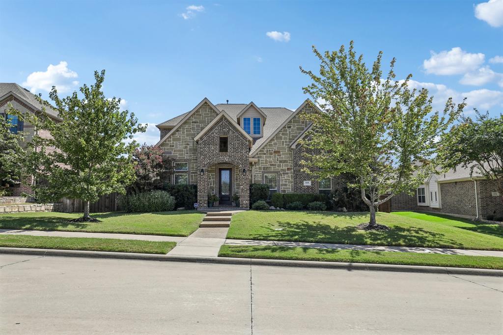 Stone exterior featuring a multi-gabled roofline, central covered entryway, and mature landscaping Stone exterior featuring a multi-gabled roofline, central covered entryway, and mature landscaping