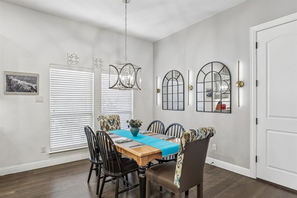 Dining area featuring wood-finish flooring, a geometric metal chandelier, two arched wall-mounted mirrors, and sleek vertical accent lighting