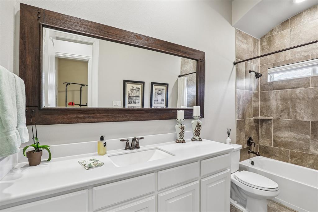 Second downstairs bathroom featuring a white vanity with an integrated sink, a large mirror with a wood-finish frame, oil-rubbed bronze plumbing fixtures, and tile tub surround