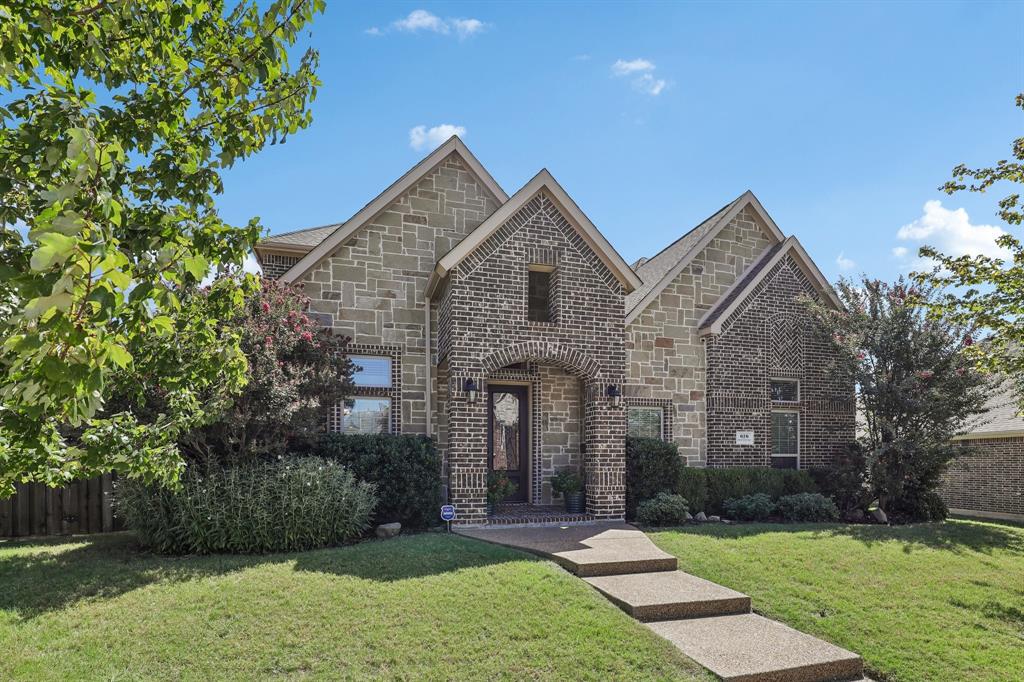 Multi-gabled exterior featuring masonry facade, arched entryway with brick detailing, and paved walkway Multi-gabled exterior featuring masonry facade, arched entryway with brick detailing, and paved walkway