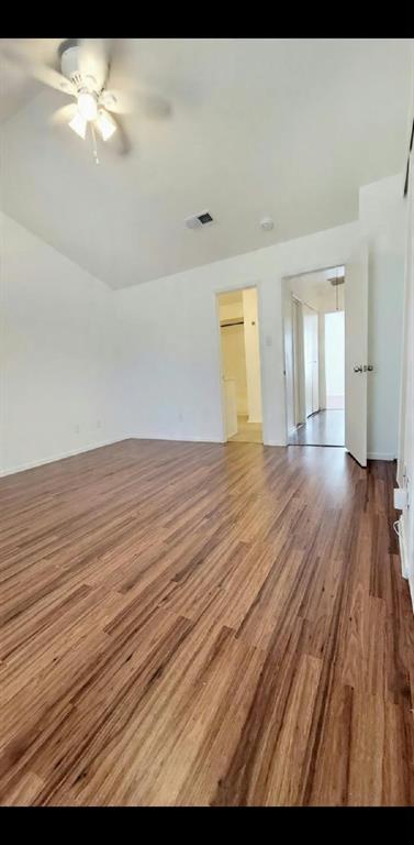 Vaulted ceiling with integrated multi-blade ceiling fan and wood-finish flooring throughout