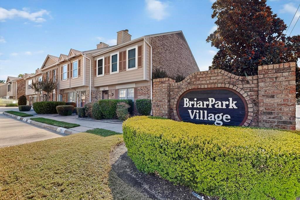 Multi-story townhome exterior featuring brick and siding facade, decorative shutters, and manicured landscaping Multi-story townhome exterior featuring brick and siding facade, decorative shutters, and manicured landscaping