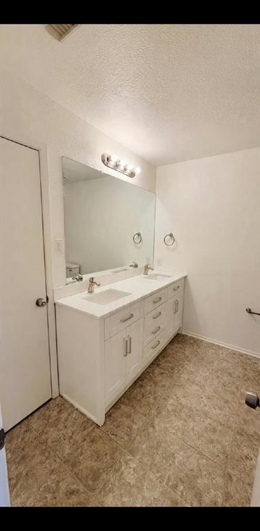 White vanity with dual integrated sinks, solid-surface countertop, full-width mirror, and four-light vanity fixture