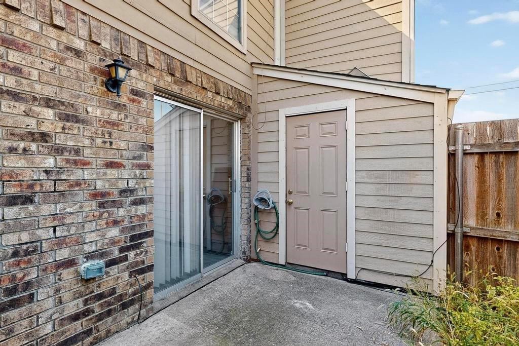 Exterior space featuring a concrete patio, brick veneer wall, horizontal siding, sliding glass door, and solid-panel door