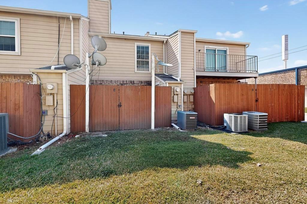 Rear exterior featuring horizontal lap siding, a second-story balcony with metal railings, and a fenced backyard area