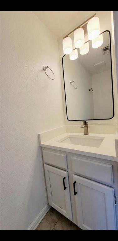 White vanity cabinet with matte black hardware, integrated rectangular sink, solid surface countertop, wall-mounted rectangular mirror with rounded corners, and multi-bulb glass light fixture