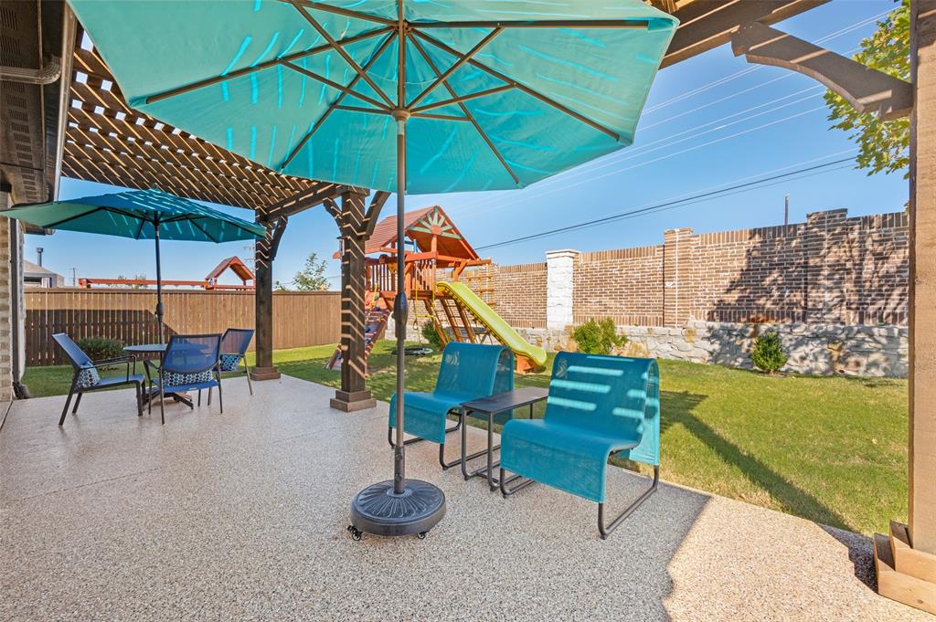 Covered patio featuring a textured concrete finish, overhead timber pergola, brick perimeter wall, and a grass lawn
