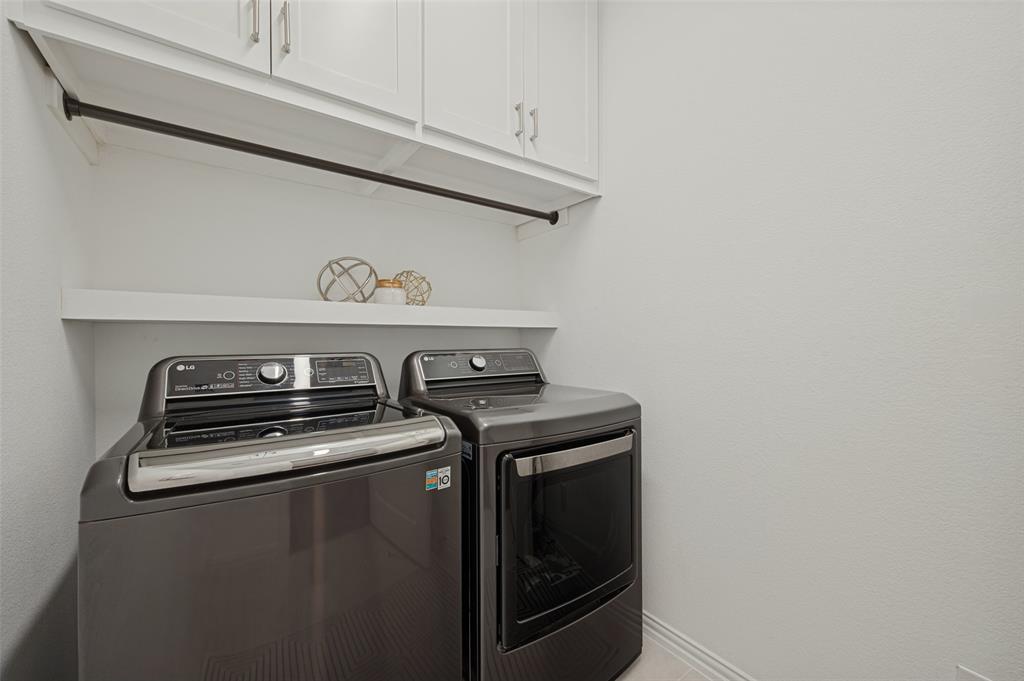 Laundry area featuring white shaker-style wall cabinetry, a mounted garment rod, and an integrated floating shelf