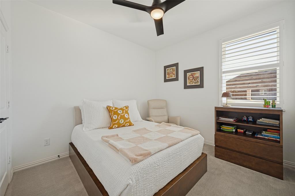 Neutral-toned wall-to-wall carpeting, window fitted with adjustable plantation shutters, and a central ceiling fan with integrated lighting