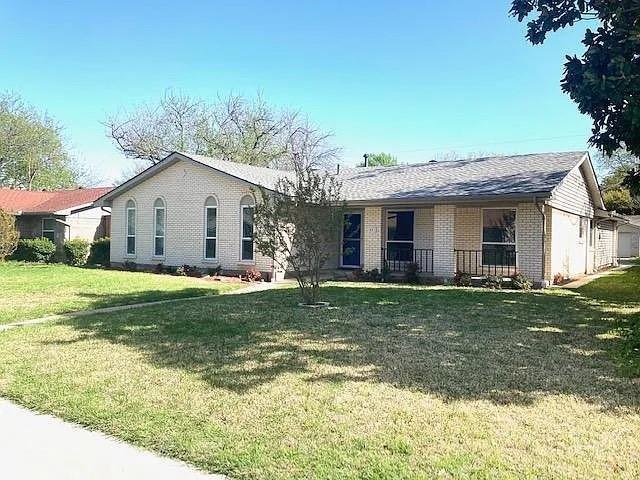 Single-story residence featuring light brick exterior, arched window detailing, a covered entryway with metal railing, and a gabled roof Single-story residence featuring light brick exterior, arched window detailing, a covered entryway with metal railing, and a gabled roof