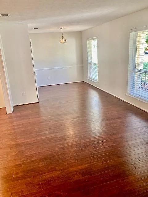 Wood-finish flooring, neutral wall tones, chair rail molding, multi-pane windows, and a suspended metal fixture Wood-finish flooring, neutral wall tones, chair rail molding, multi-pane windows, and a suspended metal fixture