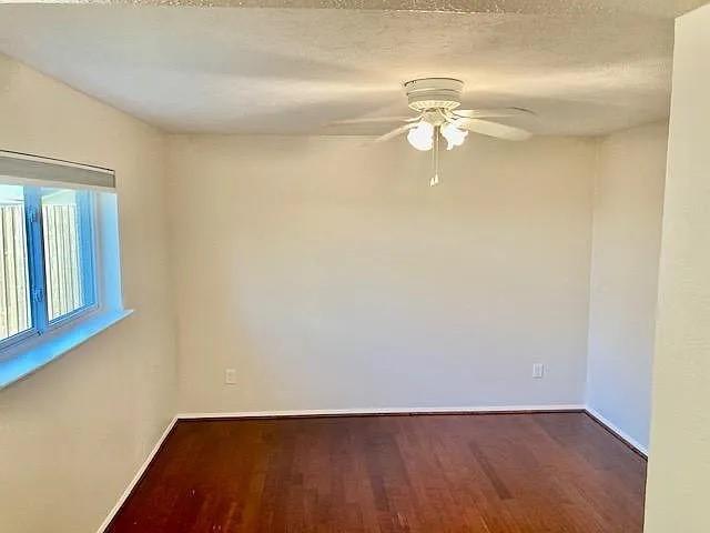 Room featuring wood-finish flooring, a white ceiling fan with integrated light fixture, and a window with a fixed sill Room featuring wood-finish flooring, a white ceiling fan with integrated light fixture, and a window with a fixed sill