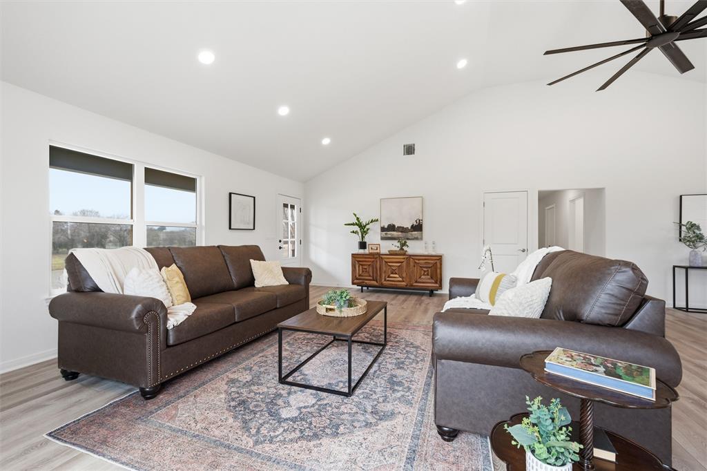 Living area featuring a vaulted ceiling, wood-finish flooring, recessed lighting, and a multi-blade ceiling fan