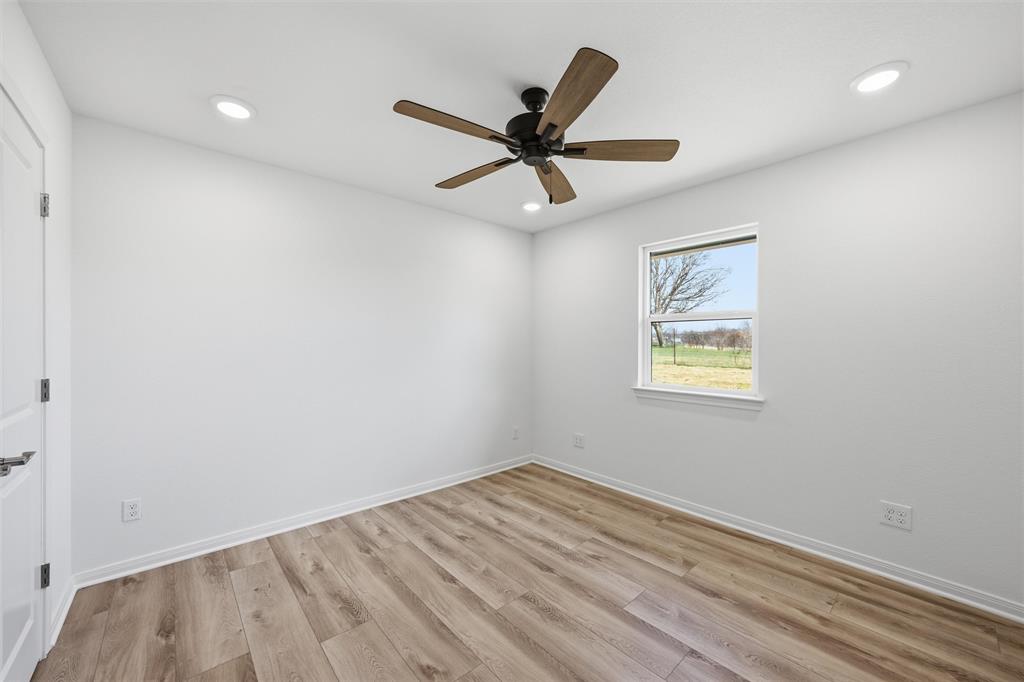 Wood-finish flooring, recessed lighting, and a ceiling fan with wood-toned blades under a single-hung window