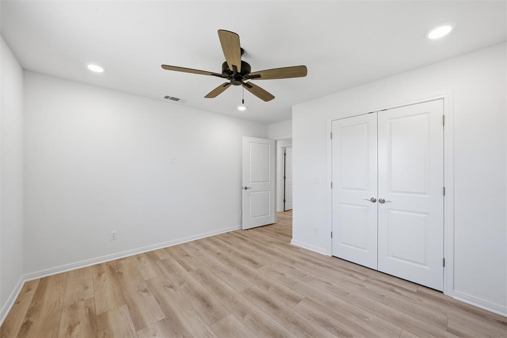 Room featuring wood-finish flooring, recessed lighting, a ceiling fan with integrated lighting, and dual-panel closet doors