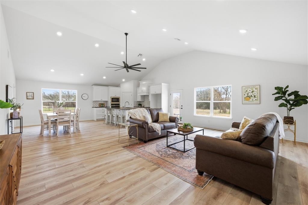 Vaulted ceilings, wood-finish flooring, recessed lighting, central ceiling fan, and white cabinetry featuring a kitchen island Vaulted ceilings, wood-finish flooring, recessed lighting, central ceiling fan, and white cabinetry featuring a kitchen island