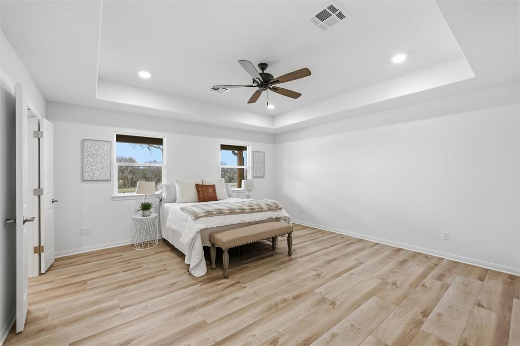 Tray ceiling with recessed lighting, wood-finish flooring, and integrated ceiling fan