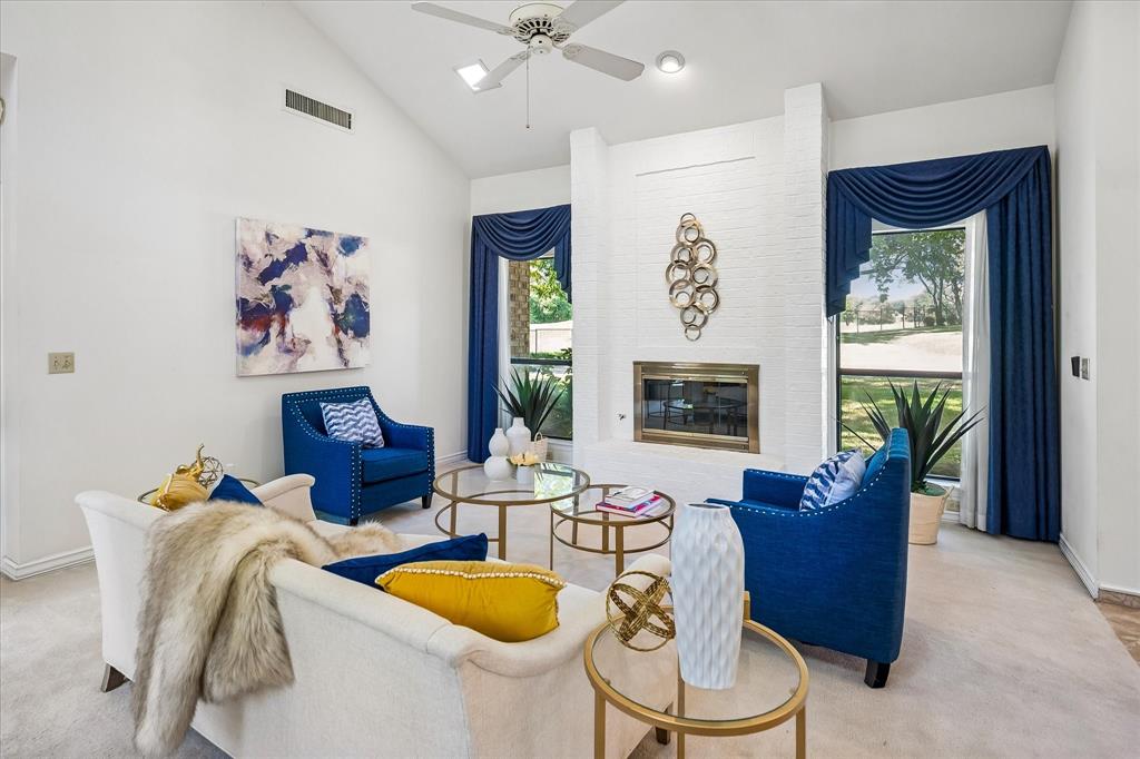 Another view of the living room with large windows brining in natural light into the home and a view of the golf course across the street.