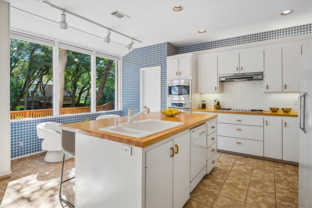 Another view of the kitchen with plenty of storage space and a view of the wonderful backyard on a creek lot with plenty of trees.