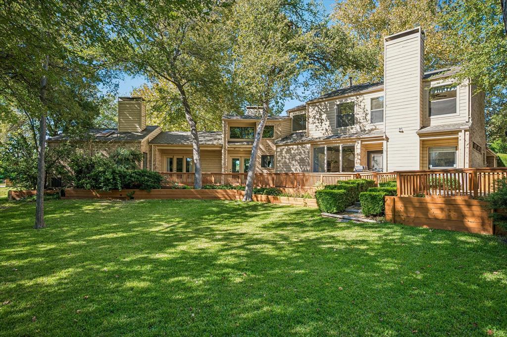 View of the back of the home with its unique architectural design and large wrap-around deck providing spectacular view of the large landscaped home and creek.