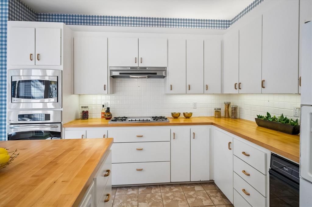 Yet another view of the kitchen with a built-in trash compactor and gas stovetop with a vented and lighted hood.