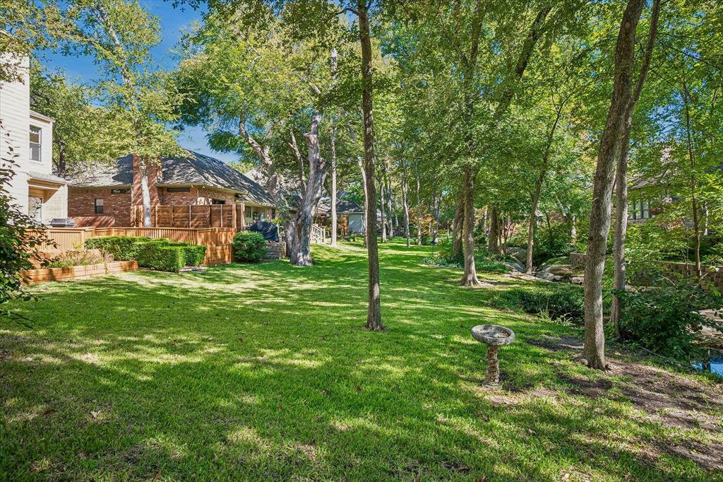 Another view of the backyard looking to the east of the home showing lots of trees and you can see the creek running across the backyard.