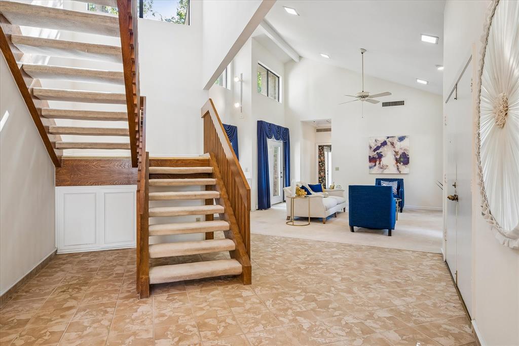 Another view of the wooden staircase with plenty of storage underneath and looking into the cathedral ceiling of the living room.  You can also see the unique round glass window facing the front of the home.