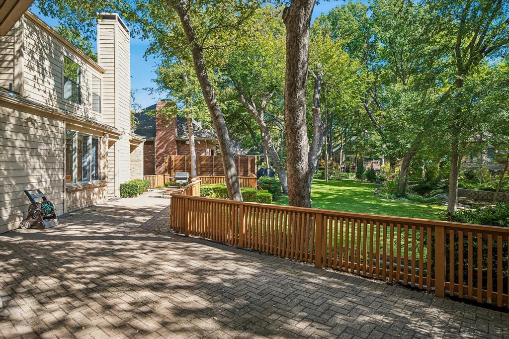 Another view of the spacious paved wrap-around deck looking out to the creek lot backyard with lots of trees.
