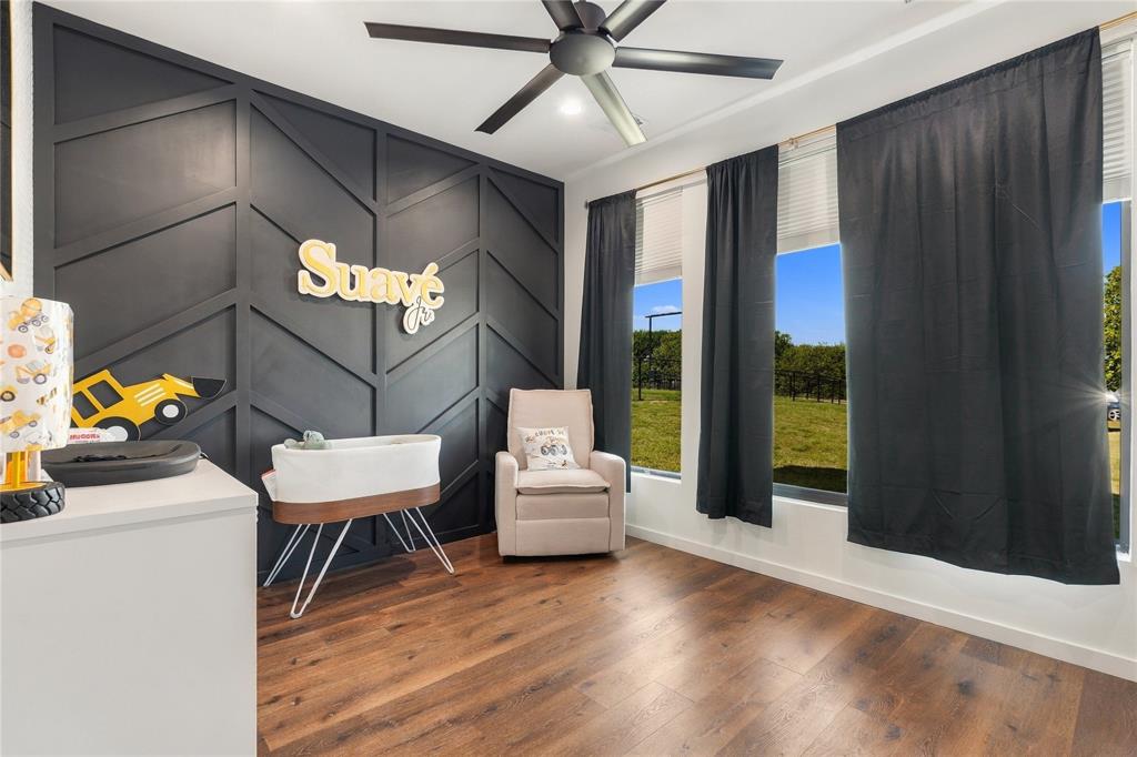 Geometric wood accent wall in a dark matte finish, wood-finish flooring, and a modern ceiling fan