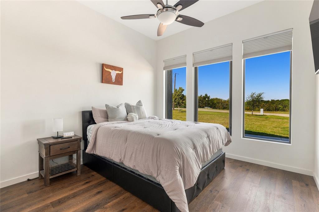 High ceilings with a multi-blade ceiling fan, wood-finish flooring, and expansive windows featuring cellular shades