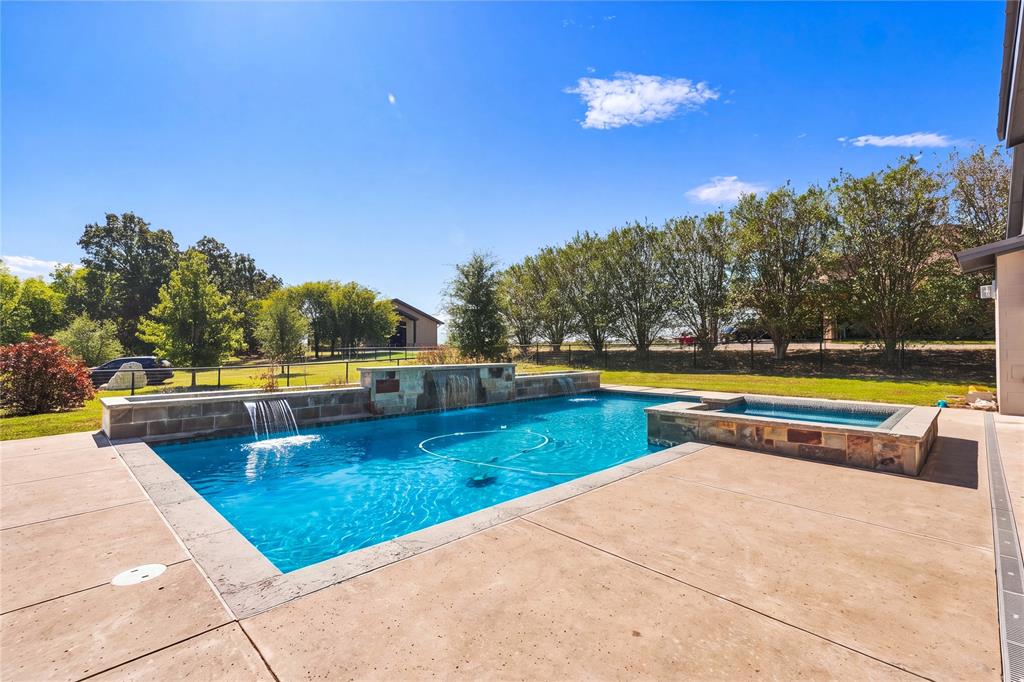 Backyard swimming pool featuring stone accents, a raised spa, water features, and a concrete patio