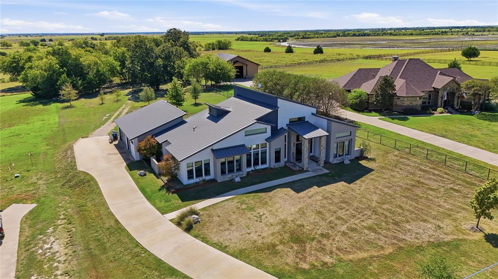 Modern residence featuring a metal roof, clean-lined contemporary exterior, stone-accented entryway, attached garage, and expansive grounds Modern residence featuring a metal roof, clean-lined contemporary exterior, stone-accented entryway, attached garage, and expansive grounds