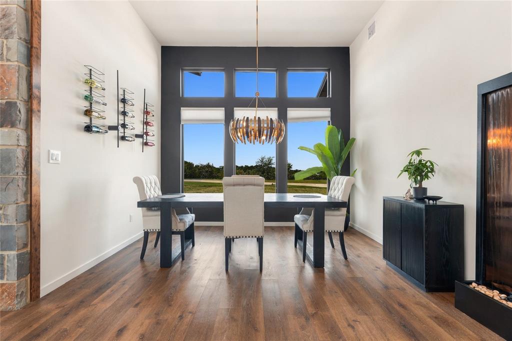 High ceilings featuring oversized windows, wood-finish flooring, wall-mounted wine storage, and a tiered metallic pendant light fixture High ceilings featuring oversized windows, wood-finish flooring, wall-mounted wine storage, and a tiered metallic pendant light fixture