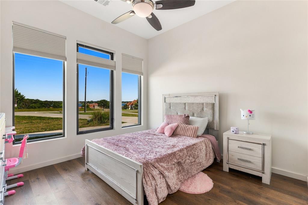 High ceilings featuring a central ceiling fan, expansive triple-pane windows, and wood-finish flooring