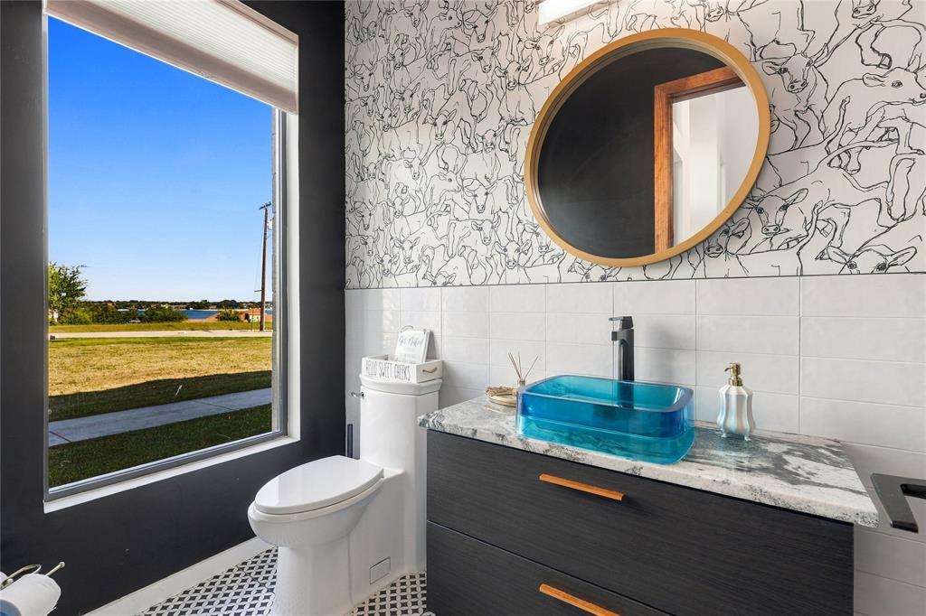 Vanity featuring a dark wood-finish cabinet with horizontal hardware, a stone-patterned countertop, and a rectangular glass vessel sink with a matte black faucet